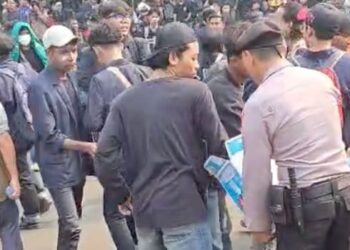 Polisi membagikan air mineral kepada demonstran di kawasan Senayan, Jakarta.