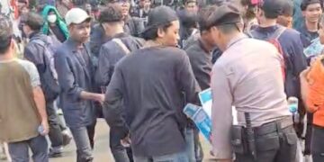 Polisi membagikan air mineral kepada demonstran di kawasan Senayan, Jakarta.