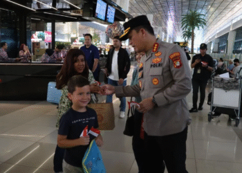 Kapolresta Bandara Soekarno-Hatta Kombes Pol Ronald FC Sipayung membagikan bendera Merah Putih kepada penumpang di Bandara Soetta, Tangerang, Banten.