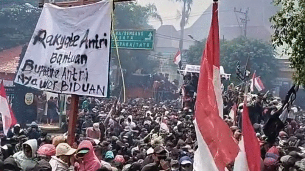 Massa aksi membawa spanduk tuntutan dalam demo di depan Kantor Bupati Pati, Rabu (13/8/2025).