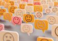 Banyak ikon emoji dalam bentuk balon percakapan berwarna kuning dan merah muda dengan berbagai ekspresi wajah.