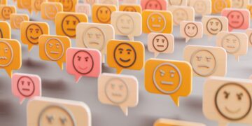 Banyak ikon emoji dalam bentuk balon percakapan berwarna kuning dan merah muda dengan berbagai ekspresi wajah.