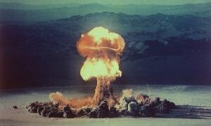 Ledakan uji coba nuklir di gurun Nevada dengan awan jamur besar menjulang ke udara.